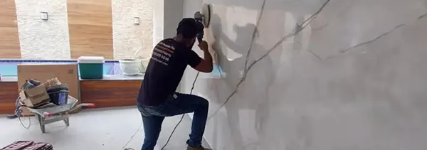 Profissional da L&M Pinturas Rio polindo parede em efeito mármore